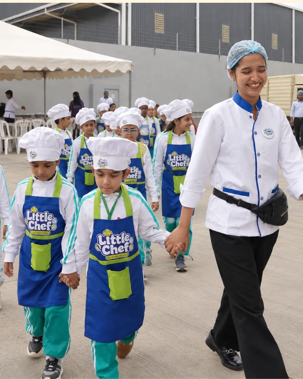 A Little Chef coordinator walking hand in hand with the children